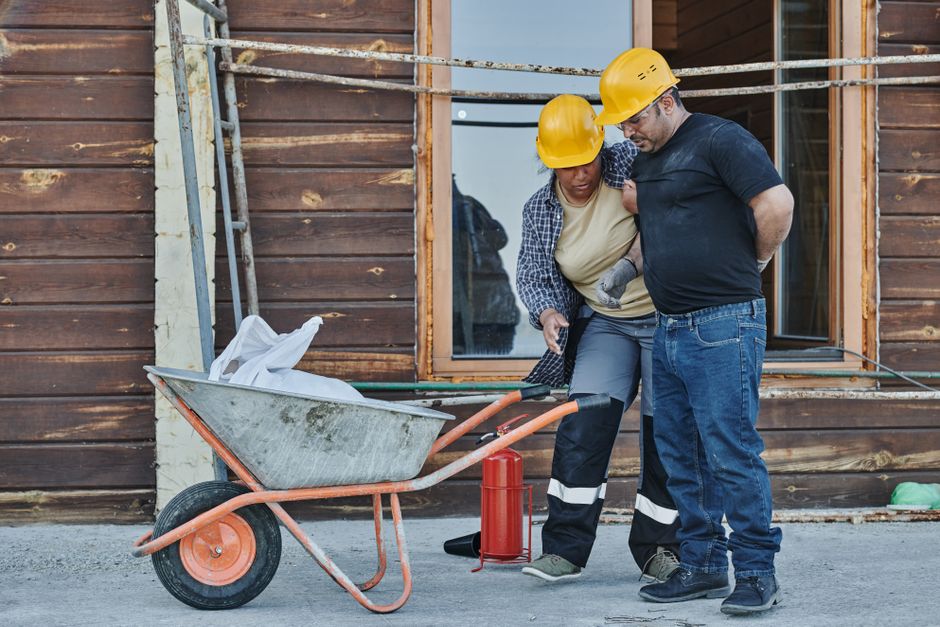 A construction worker helping an injured coworker on site
